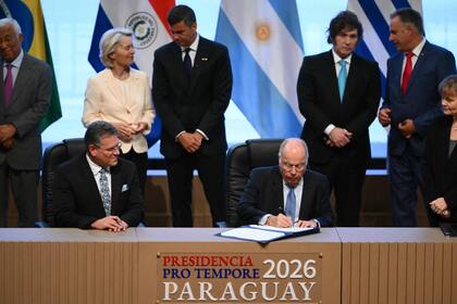 El canciller brasileño Mauro Vieira firma un documento del Mercosur, con el presidente argentino Javier Milei detrás