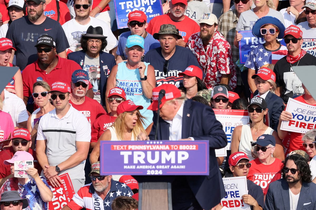 El candidato presidencial republicano Donald Trump al recibir el disparo del tirador en su oreja derecha. Atrás a su derecha se ve a una mujer de gorra negra y anteojos de sol que se queda quieta frente al hecho (REUTERS/Brendan McDermid)