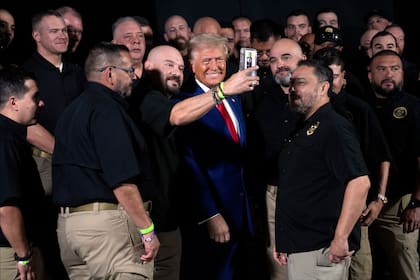 El candidato presidencial republicano Donald Trump sonríe para una selfie con miembros de la Patrulla Fronteriza de Estados Unidos antes de hablar en un mitin de campaña, el 13 de octubre de 2024, en Prescott Valley, Arizona. (AP/Evan Vucci)