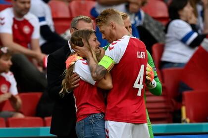 El capitán de Dinamarca, Simon Kjaer, y el arquero Kasper Schmeichel tratan de tranquilizar a Sabrina Kvist Jensen, la novia de Christian Eriksen, mientras el jugador es atendido en el campo.
