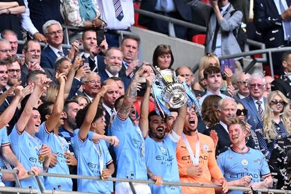 El capitán y figura de la final, Ilkay Gundogan, levanta el trofeo junto a sus compañeros luego del triunfo en Wembley por 2-1 sobre Manchester United; el City se quedó también con la FA Cup.