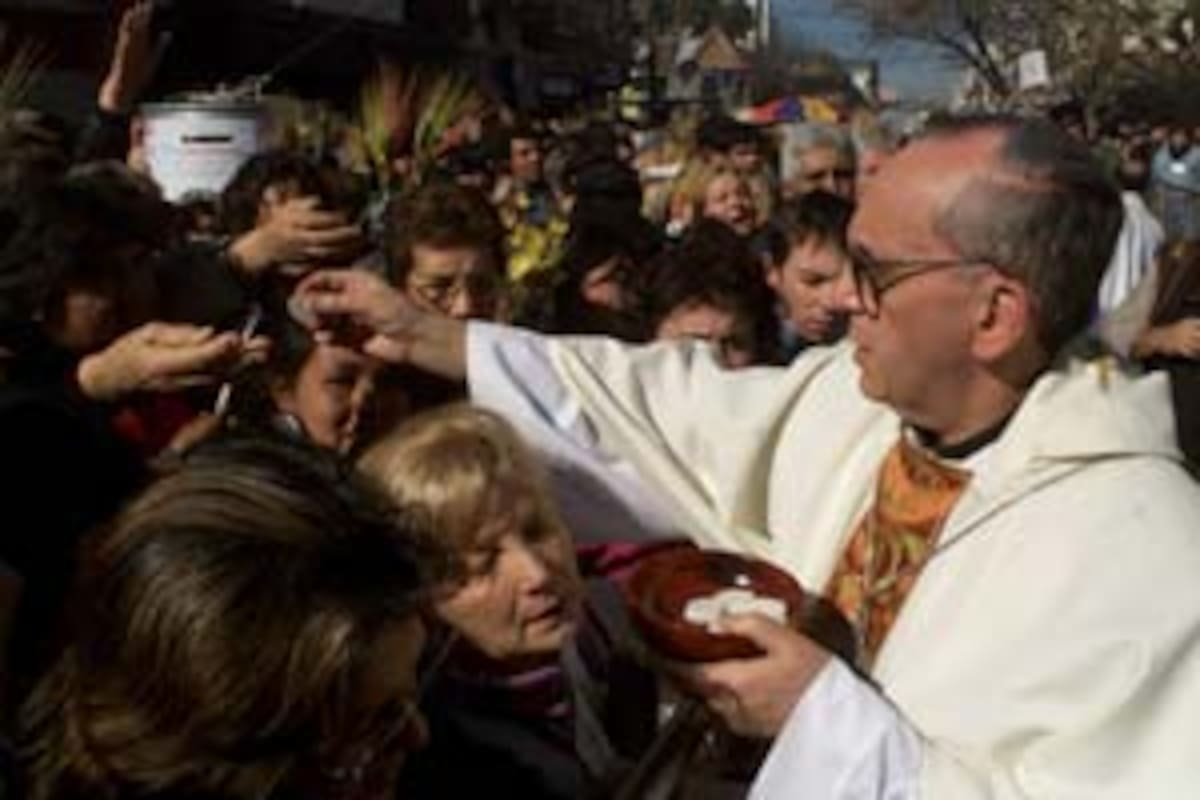 El cardenal Jorge Bergoglio imparte la comunión a los feligreses que se acercaron a pedir pan y trabajo o a agradecerle al santo