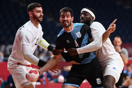 El central argentino Sebastian Simonet (C) es desafiado por el pivote francés Ludovic Fábregas (L) y el lateral derecho francés Dika Mem durante el partido de balonmano del grupo A de la ronda preliminar masculina entre Francia y Argentina de los Juegos Olímpicos de Tokio 2020 en el Estadio Nacional Yoyogi en Tokio. el 24 de julio de 2021.
