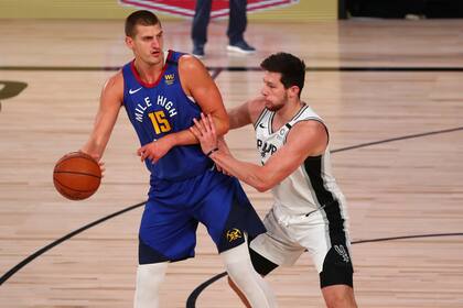 El centro de los Denver Nuggets, Nikola Jokic (15) conduce contra el alero de los San Antonio Spurs Drew Eubanks (14) durante la primera mitad de un partido de baloncesto de la NBA, el miércoles 5 de agosto de 2020 en Lake Buena Vista.