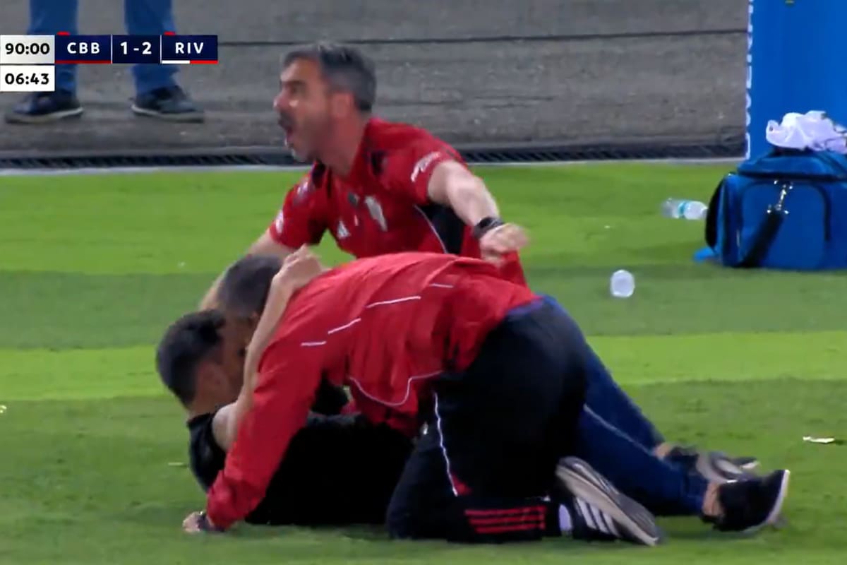 El "Chacho" Coudet festeja el triunfo en el piso, abrazado a sus asistentes, tras el agónico gol de Salas para el 2-1 de River