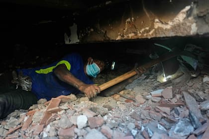 El civil Franklin Rodríguez busca a familiares desaparecidos entre los escombros de su edificio de apartamentos que se derrumbó tras los sismos ocurridos en La Guaira