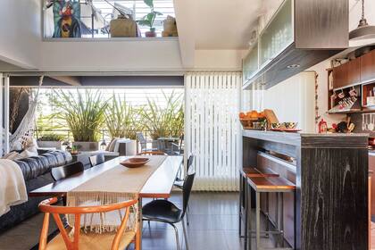 Una barra separa el living comedor de la cocina. Junto a ella se dispusieron banquetas altas.