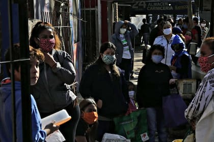 Una fila de personas espera frente a uno de los comedores a que se inicie el reparto de alimentos