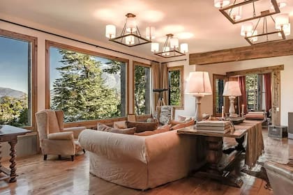 El comedor, ubicado dentro del living, tiene capacidad para 16 personas y está rodeado de ventanales que permiten disfrutar de la luz natural y las impresionantes vistas al bosque y al lago