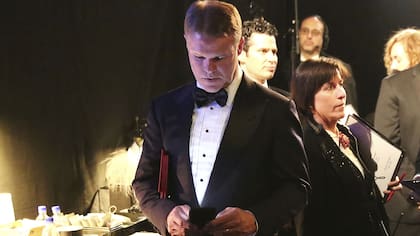 El contador de PwC, Brian Cullinan, con los sobres de los ganadores bajo el brazo mientras ve su celular