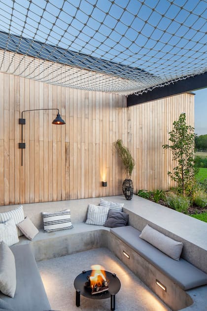 El conversation pit, un rincón íntimo que fomenta la conversación y organiza las reuniones, se hizo con una combinación de cemento alisado y porcelanato ‘Granza Ivory’ de Vite (SBG). Los almohadones se eligieron por su versatilidad, con fundas impermeables se adaptan tanto a la red como a la pileta.