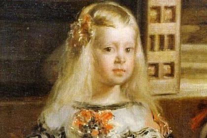 La infanta Margarita luce un exuberante vestido color crema y su cabello dorado y mejillas rosadas parecen brillar, reflejando un haz de luz natural que se filtra hacia la pintura. La pequeña princesa es uno de los pocos elementos de luminosidad en toda la composición