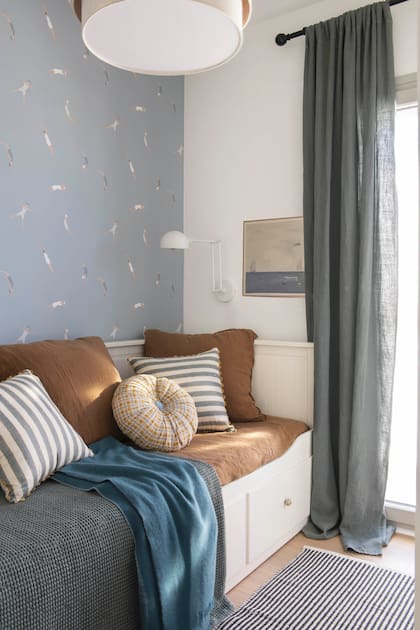 El cuarto de huéspedes suma interés con el empapelado ‘Funny Swim’ (Piccolo Mondo) contrastado con la ropa de cama en color whisky y las cortinas en lino azul (todo de Filocolore). Cama nido con cajones (Ikea) y aplique de pared (Suenh).