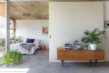 El cuarto queda integrado al living o se puede cerrar con la puerta corrediza que se superpone sobre la pared. Cómoda vintage restaurada (Mercado Libre).