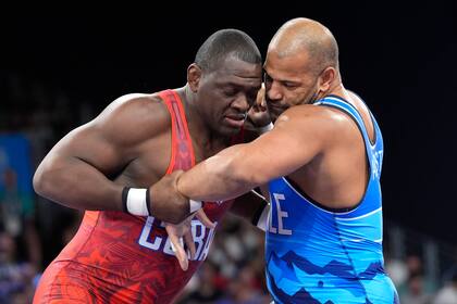 El cubano Mijaín López y el chileno Yasmani Acosta (derecha) compiten en la final de los 130 kilogramos de la lucha grecorromana de los Juegos Olímpicos de París, el martes 6 de agosto de 2024. (AP Foto/Eugene Hoshiko)