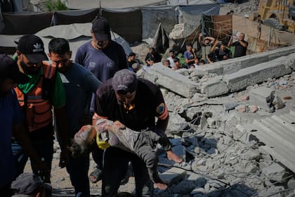 El cuerpo de un chico es retirado de entre los escombros de un edificio derrumbado, en Ciudad de Gaza
