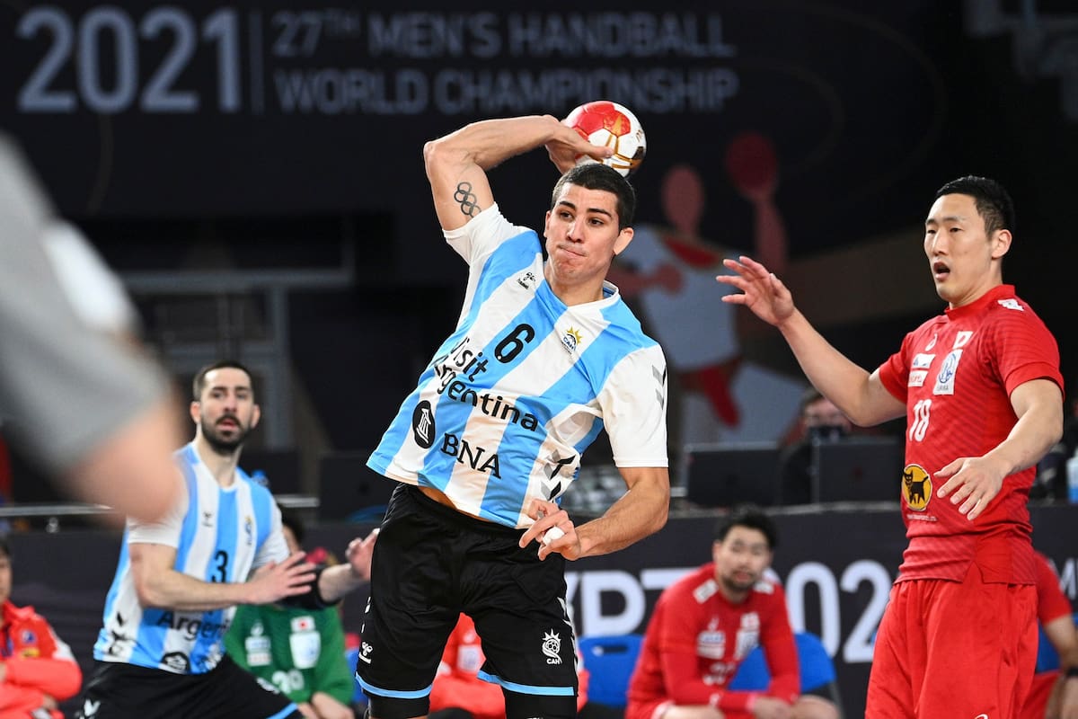 El defensa central de Argentina Diego Simonet (C) dispara al lateral izquierdo de Japón Kohei Narita durante el partido del Campeonato Mundial de Balonmano Masculino 2021 entre los equipos del Grupo II Japón y Argentina en el Palacio de Deportes del Estadio de El Cairo en la capital egipcia el 21 de