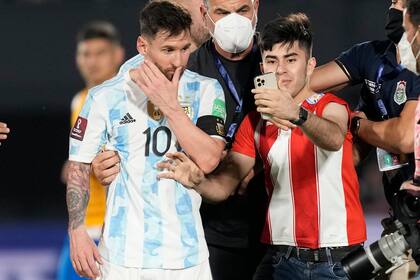 El delantero argentino Lionel Messi se retira de la cancha mientras un aficionado se toma una selfie al final del partido contra Paraguay por las eliminatorias de la Copa Mundial, el jueves 7 de octubre de 2021. (AP Foto/ Jorge Saenz)