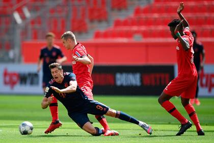 El delantero polaco del Bayern Múnich Robert Lewandowski (L) cae junto al defensor alemán de Leverkusen Sven Bender (C) y el defensor burkinabe de Leverkusen Edmond Tapsoba durante el partido de fútbol de la Bundesliga de la primera división alemana