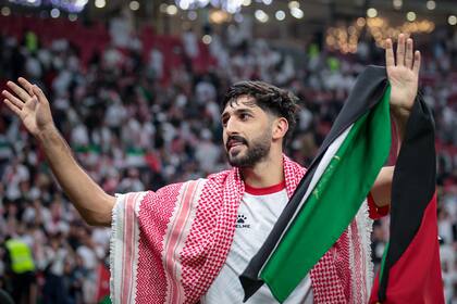 El delantero Yazan Al-Naimat celebra con la bandera de Jordania, un país que vibra con la primera clasificación para el Mundial.