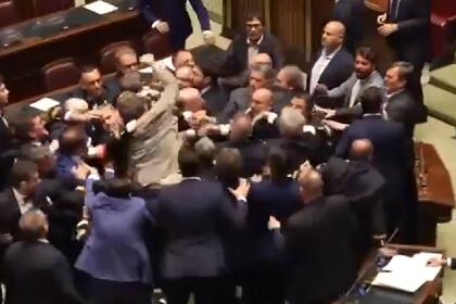 El diputado Iezzi, de traje claro, levanta el puño para golpear a Donno. (Captura de TV)