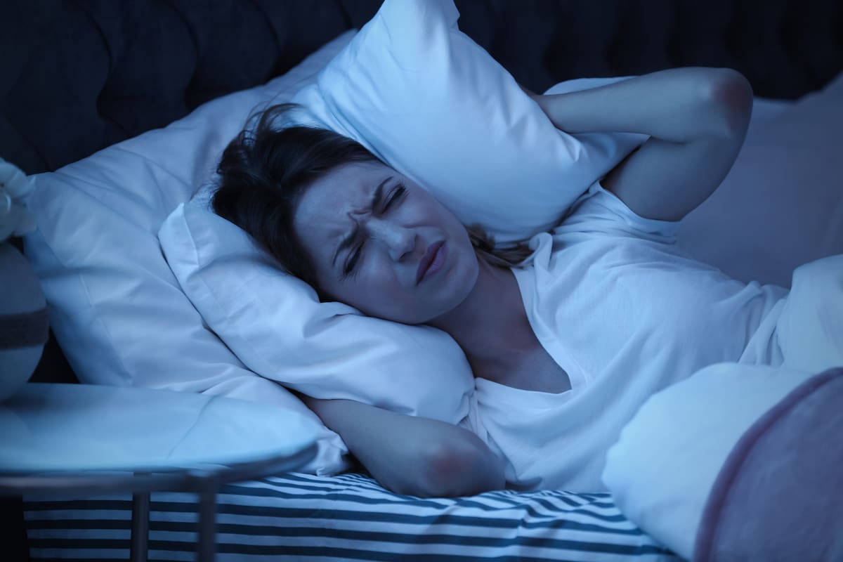 El dolor se trata de un sistema de alarma que posee nuestro cerebro para decirnos que estamos en riesgo y que insta a ponerse a salvo
Young woman covering ears with pillow while trying to sleep in bed at night