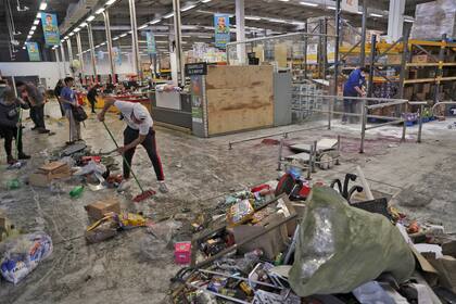 Varios empleados limpian un supermercado que fue saqueado durante las protestas