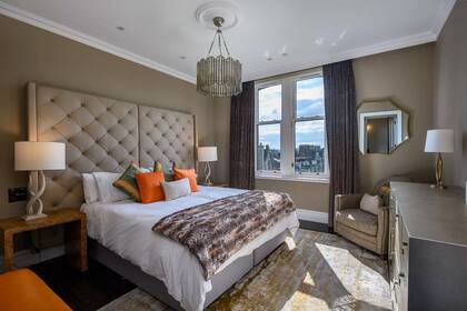 El dormitorio principal cuenta con una cama doble, una cómoda y un sillón.