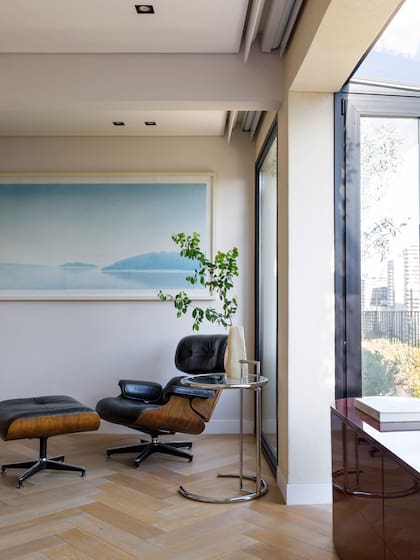 El dormitorio principal, entelado en rafia, aloja dos clásicos modernos: la poltrona ‘Eames’ y la mesita de Eileen Gray.