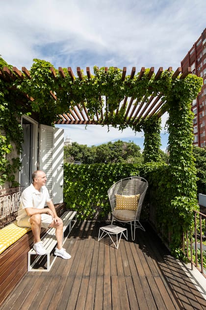 El dueño de casa a la sombra de la pérgola diseñada en hierro con la misma terminación oxidada del portón de calle del edificio.