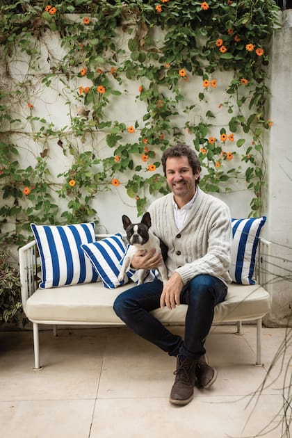 El dueño de casa posa con Pebeta, su bulldog francesa. Detrás de ellos, el jardín vertical que hizo el propio Sebastián.