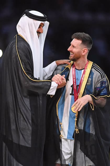 El emir distingue a Lionel Messi al colocarle un bisht, la tradicional bata que sólo usan altos dignatarios en Qatar.