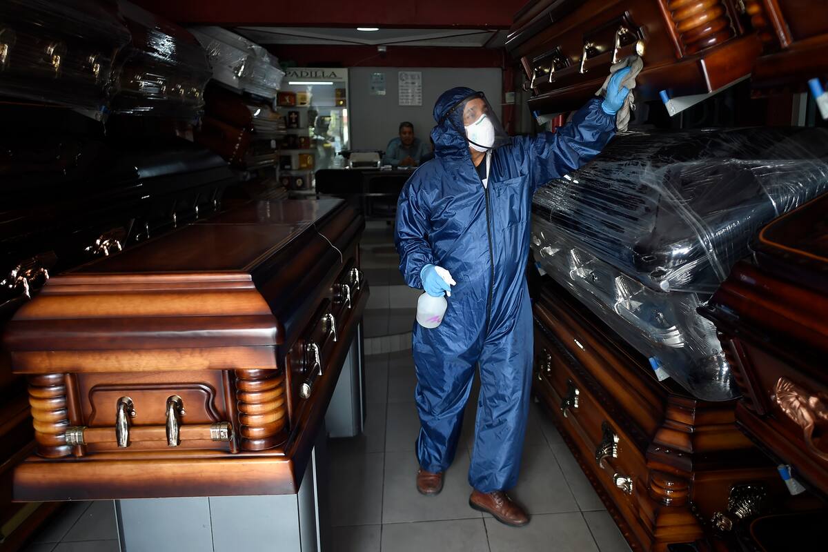 El empleado mexicano de la funeraria Antonio Padilla desinfecta los ataúdes, en Ciudad Nezahualcóyotl, estado de México, el 7 de mayo de 2020, en medio de la pandemia de coronavirus