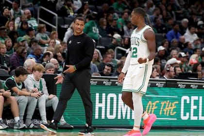 El entrenador en jefe de los Celtics de Boston, Joe Mazzulla, al frente a la izquierda, habla con el escolta de los Celtics, Lonnie Walker IV (12), quien camina hacia el banquillo del equipo durante la segunda mitad de un partido de baloncesto de la NBA de pretemporada contra los Raptors de Toronto, el domingo 13 de octubre de 2024, en Boston. (AP Foto/Mark Stockwell)
