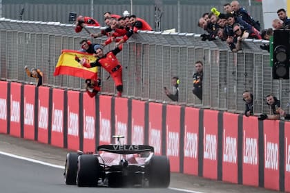 El equipo de Ferrari ondea una bandera española mientras el piloto español Carlos Sainz Jr cruza la línea finlandesa primero para ganar el Gran Premio de Gran Bretaña de Fórmula Uno en el circuito de carreras de Silverstone en Silverstone, centro de Inglaterra, el 3 de julio de 2022. (Foto de JUSTIN TALLIS / AFP)