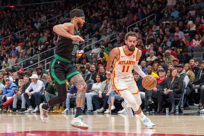 El escolta de los Hawks de Atlanta, Trae Young (11), conduce por el carril mientras es custodiado por el alero de los Celtics de Boston, Jayson Tatum (0), durante la primera mitad de un partido el lunes 4 de noviembre de 2024, en Atlanta. (AP Foto/Jason Allen)