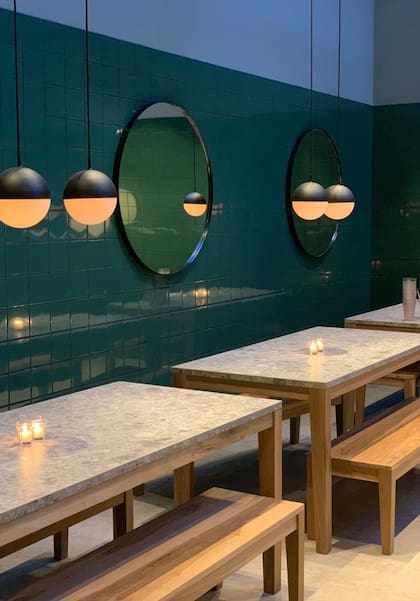 El espacio que rodea a la cocina está armado con dos mesas comunitarias en un ambiente que se asemeja a una pecera