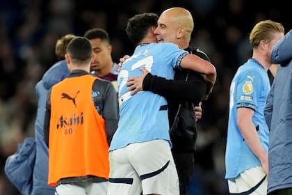El español Pep Guardiola, técnico del Manchester City, festeja con Matheus Nunes tras la victoria sobre el Aston Villa, el martes 22 de abril de 2025 (Martin Rickett/PA via AP)