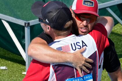 El estadounidense Vincent Hancock abraza a su compatriota Conner Lynn Prince, luego que ambos ganaron el oro y la plata, respectivamente, en la modalidad de skeet del tiro olímpico, el sábado 3 de agosto de 2024, en Chateauroux, París (AP foto/Manish Swarup)