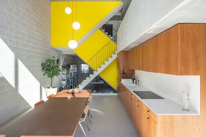 El estudio de arquitectura holandés BETA construyó esta casa en Ámsterdam para una familia multigeneracional con una escalera amarilla central que conecta todos los ambientes y a sus integrantes