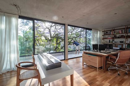 El estudio tiene una mesa para el teclado, una grande para trabajar en equipo y una biblioteca a medida (todo de Talleres Sustentables). Silla (Landmark), sillón de cuero (Manifesto). Cortinas (Patricia López).