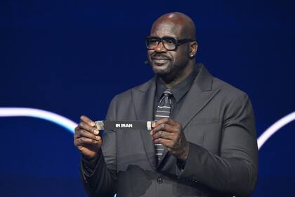 El ex basquetbolista de NBA Shaquille O'Neal sostiene el papel con el nombre de Irán durante el sorteo de la composición de las zonas.