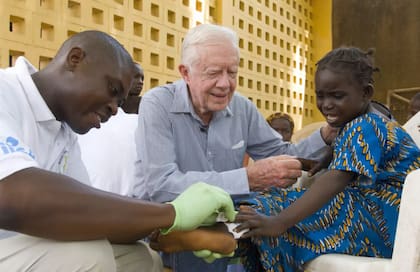 El ex presidente Carter consuela a Ruhama Issah, de 6 años, mientras Adams Bawa, voluntario del Centro Carter, le cura una herida en la mano en el Hospital Savelugu de Ghana.