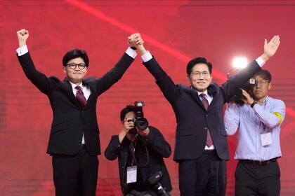 El exlíder del Partido del Poder del Pueblo Han Dong-hun (izquierda), y el exministro de Trabajo de Corea del Sur Kim Moon Soo saludan con los brazos en alto durante una convención de la formación en Goyang, Corea del Sur, el 3 de mayo de 2025