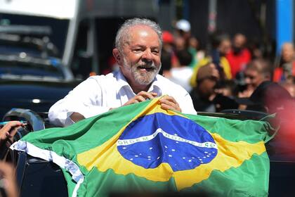 El expresidente brasileño (2003-2010) y candidato del izquierdista Partido de los Trabajadores (PT) Luiz Inacio Lula da Silva sostiene una bandera brasileña mientras sale de un colegio electoral durante la segunda vuelta de las elecciones presidenciales, en Sao Paulo, Brasil, el 30 de octubre de 2022.