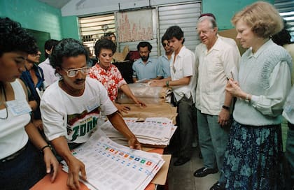 El expresidente de EEUU Jimmy Carter y su esposa Rosalynn, derecha, observan mientras trabajadores electorales preparan boletas en un centro de votación en Managua, Nicaragua, el 25 de febrero de 1990. Los Carter fueron a Nicaragua como observadores electorales.