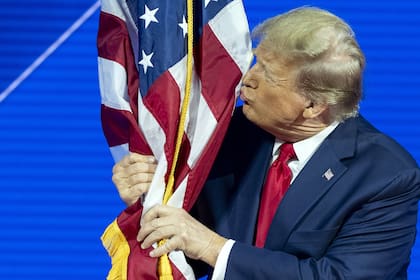 El expresidente Donald Trump besa la bandera norteamericana en la Conferencia Política de Acción Conservadora (CPAC), en el centro de convenciones del resort Gaylor National. (AP/Alex Brandon)