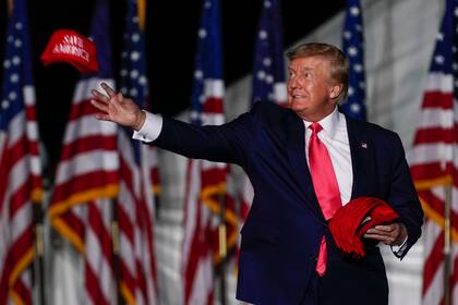 El expresidente Donald Trump lanza gorras al público al llegar a un mitin el viernes 5 de agosto de 2022, en Waukesha, Wisconsin (AP Foto/Morry Gash)