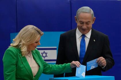 El exprimer ministro de Israel y candidato del partido Likud, Benjamin Netanyahu, y su esposa Sara, gesticulan tras conocerse los resultados de las primeras encuestas de salida de las elecciones parlamentarias, en la sede de la formación en Jerusalén, el 2 de noviembre de 2022. (AP Foto/Tsafrir Abayov)