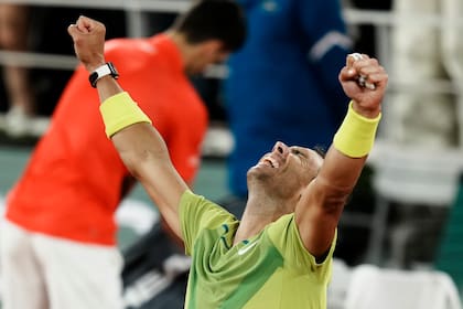 El final en París: Rafael Nadal alza sus brazos luego de una victoria épica; detrás, el campeón saliente de Roland Garros, Novak Djokovic guarda sus raquetas tras la derrota y la eliminación.